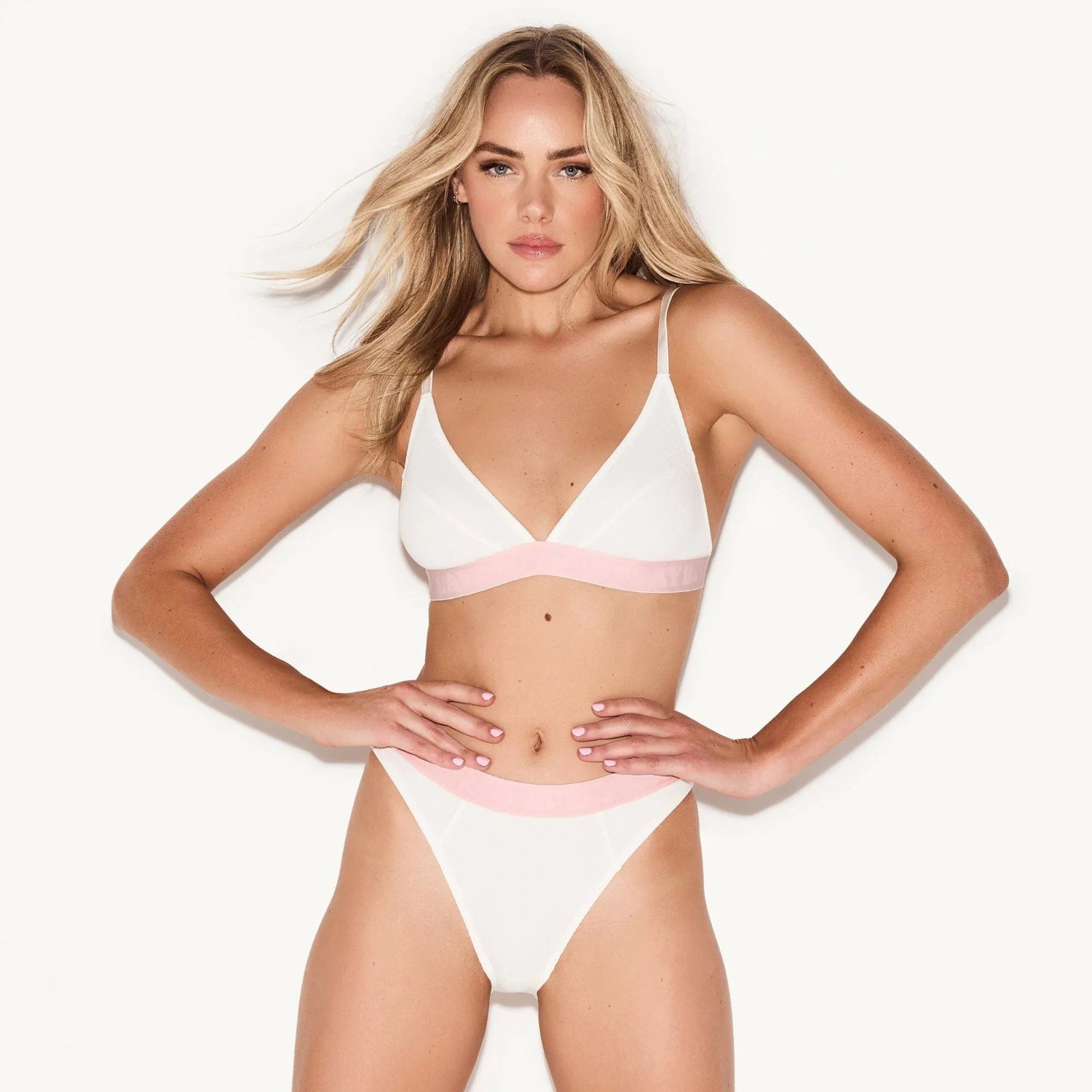 Woman wearing white rib triangle bralette and high-waisted panties with pink trim