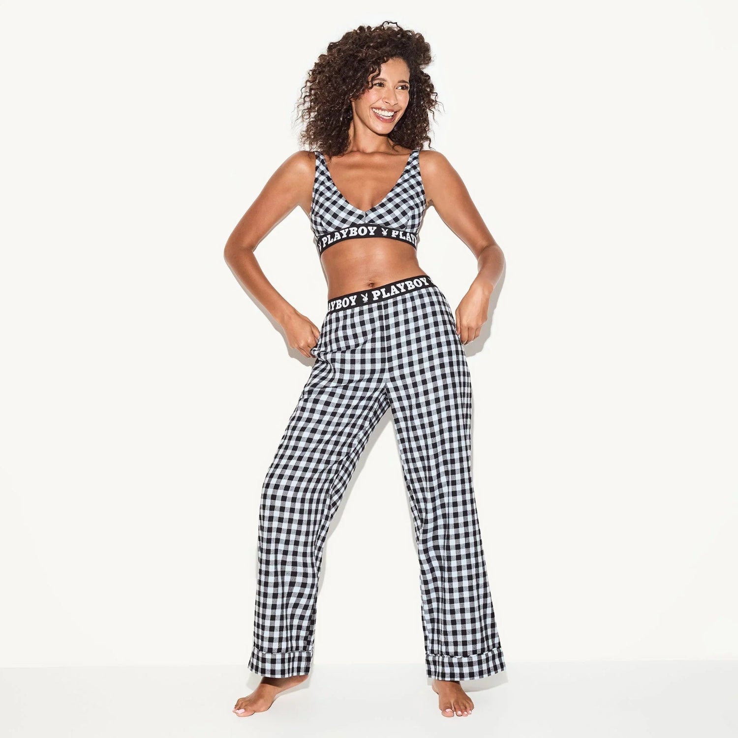 Woman wearing matching black and white plaid flannel pajama pants and crop top