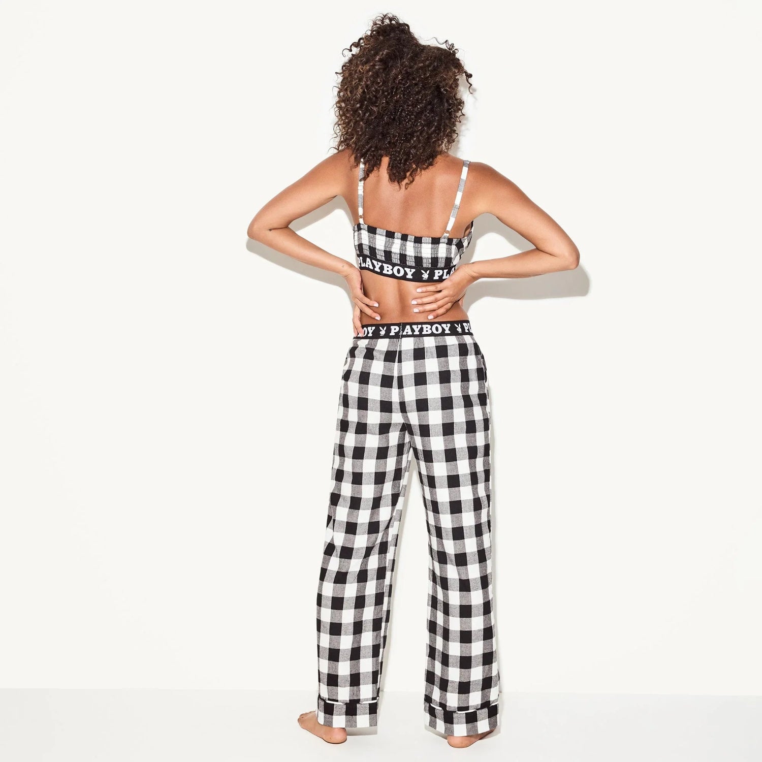 Woman wearing black and white plaid flannel pajama pants and matching bralette set, back view
