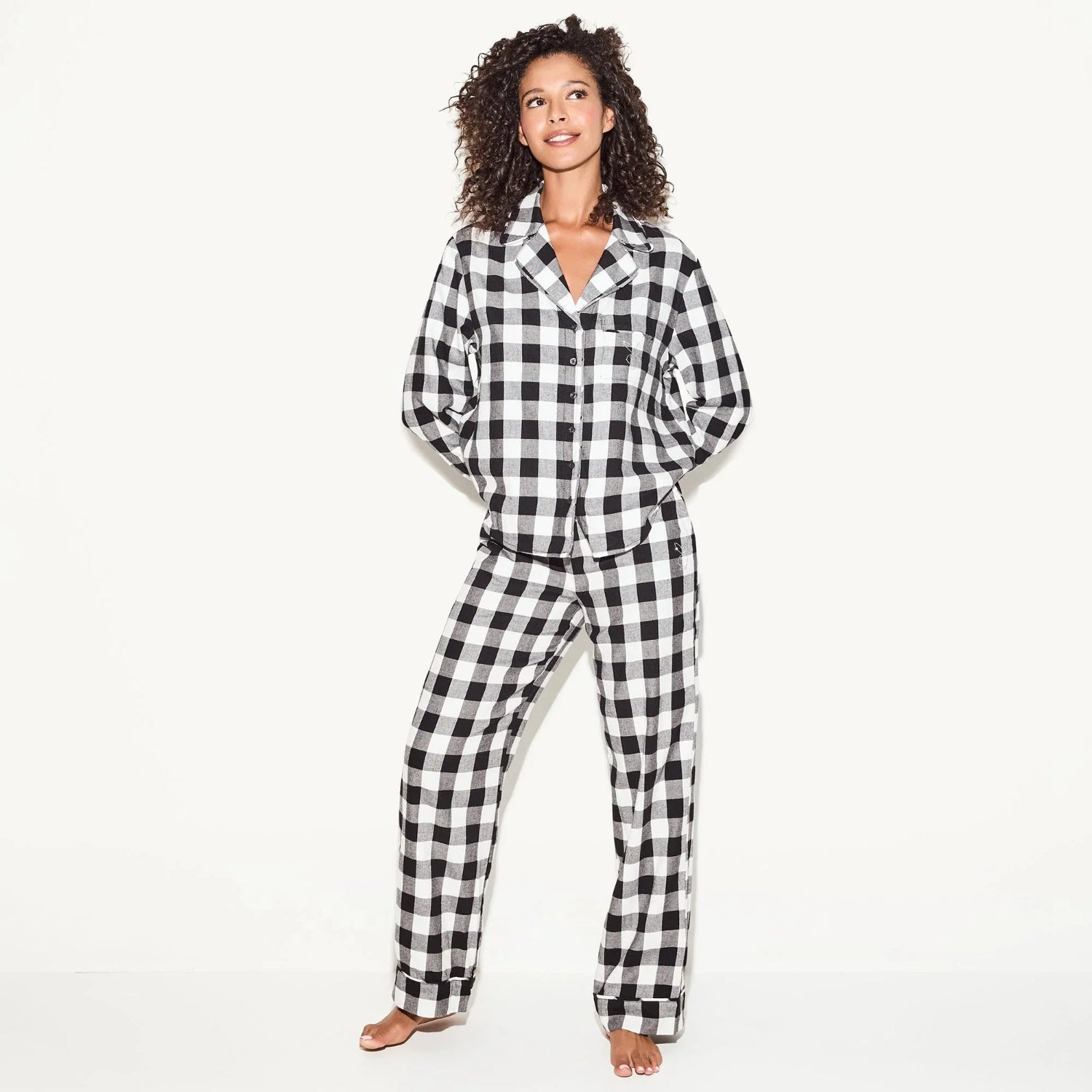Woman wearing black and white plaid flannel sleep shirt and pajama pants set