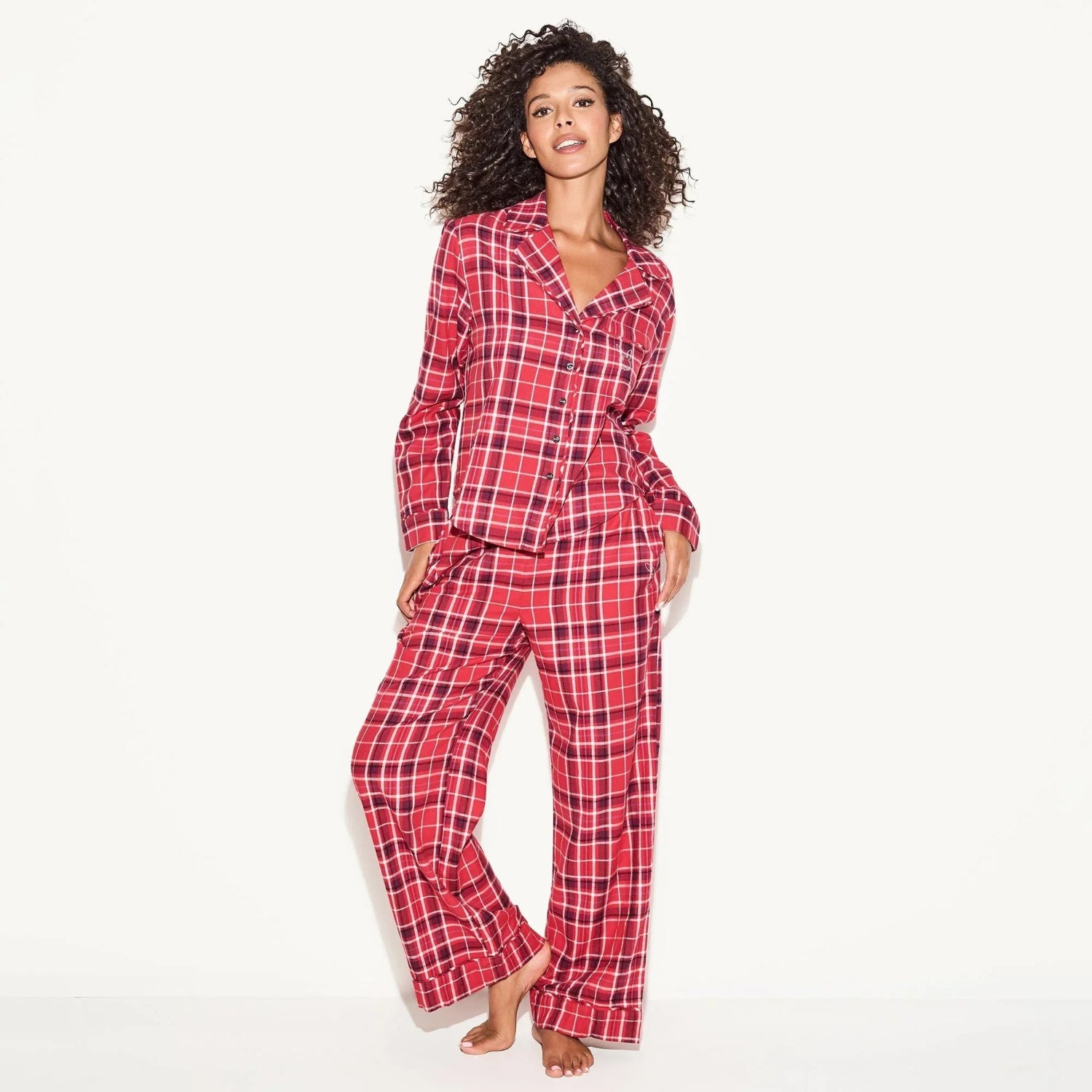 Woman wearing red plaid flannel pajama set, button-up sleep shirt and pants.