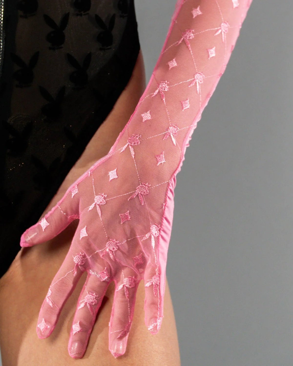 Sheer pink mesh gloves with embroidered pattern, worn with black bodysuit featuring bunny print