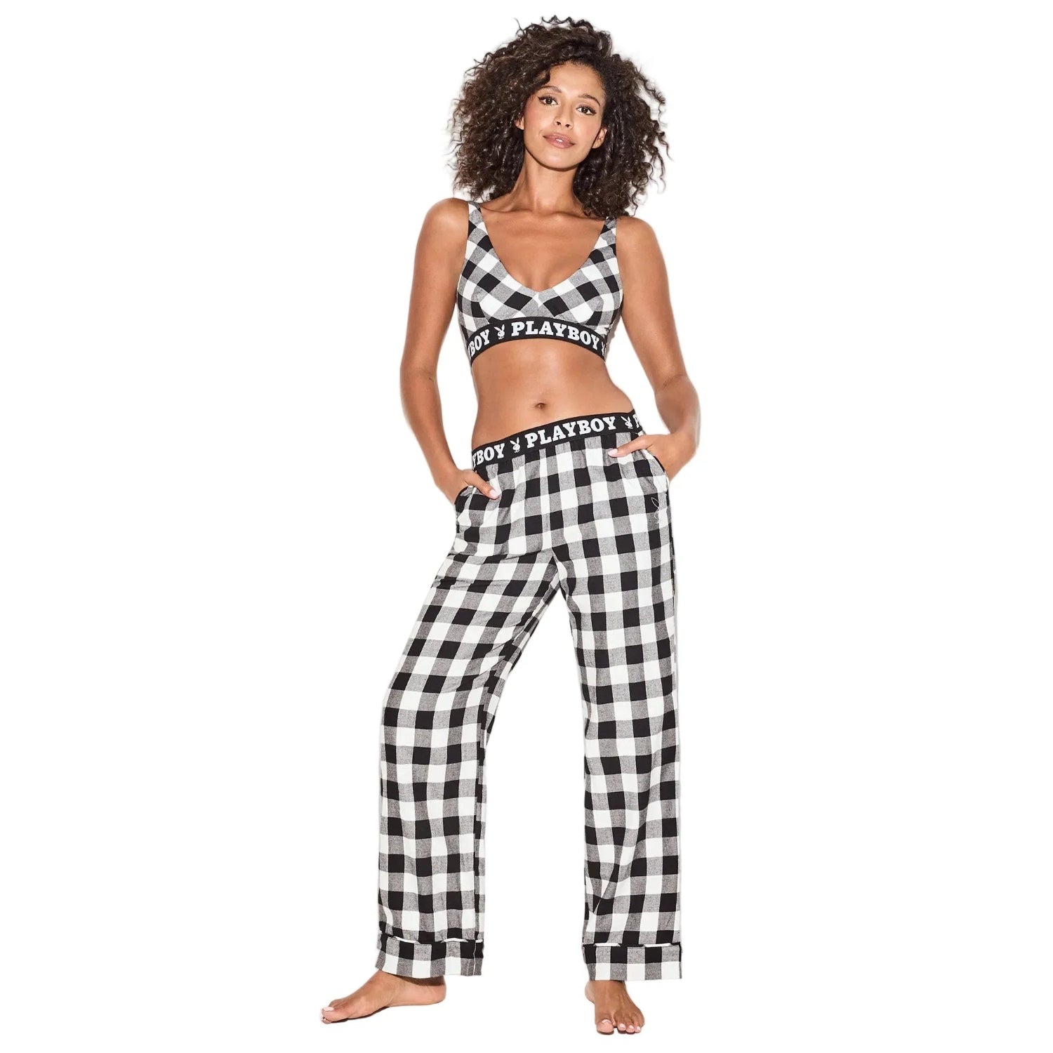 Woman in black and white plaid flannel pajama set with branded waistband, hands in pockets
