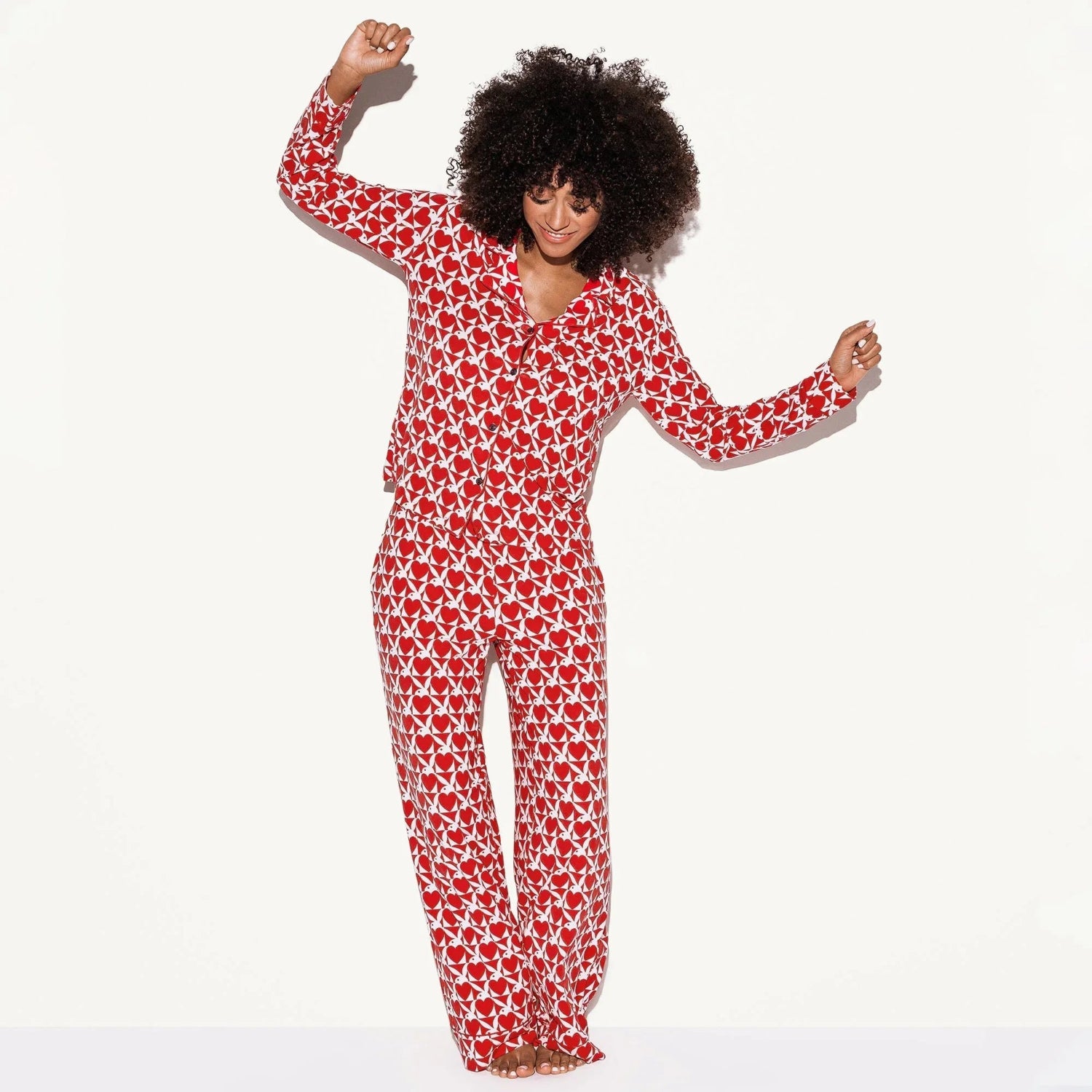 Woman wearing red and white print pajama set, long sleeve top and pants, on white background