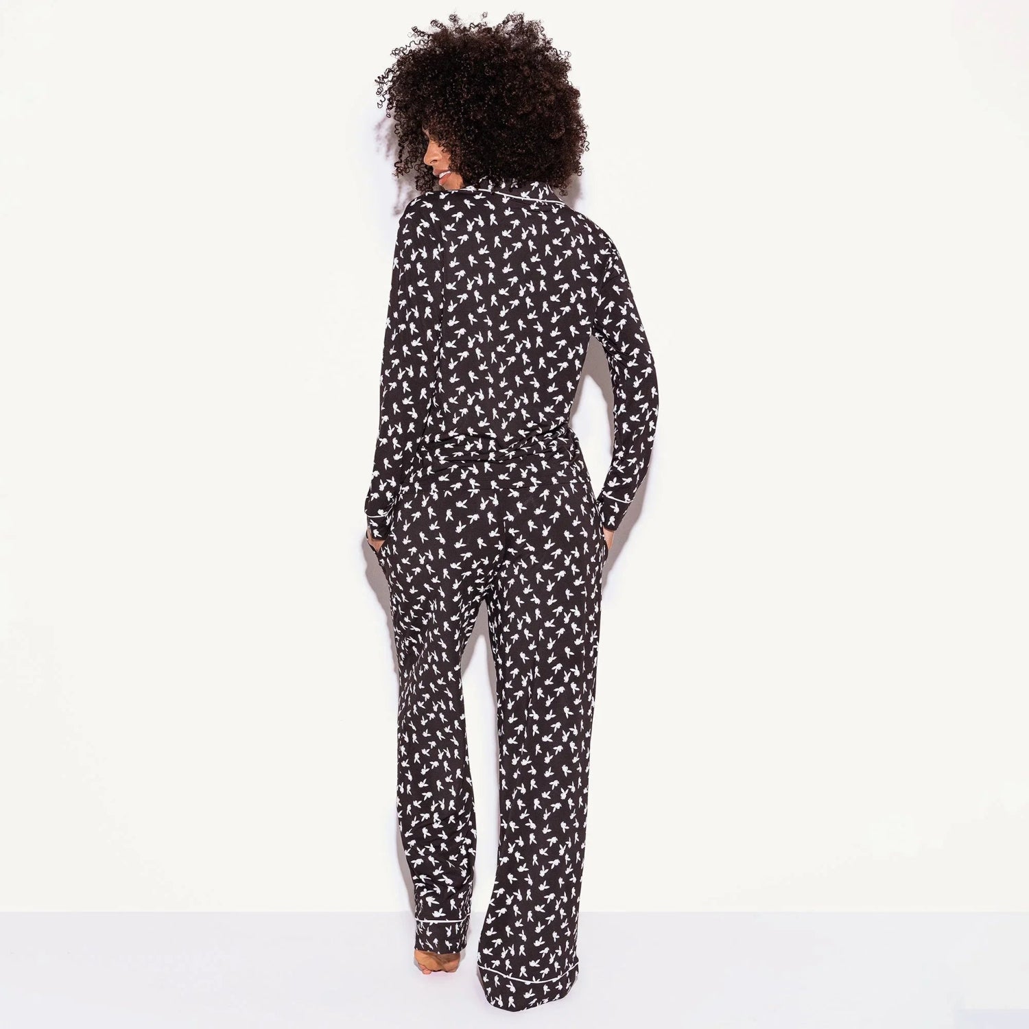 Woman wearing black pajama set with white bunny print, shown from the back
