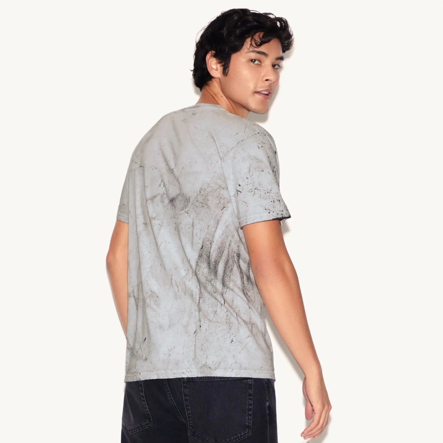 Man wearing gray distressed t-shirt with abstract black patterns, viewed from the back