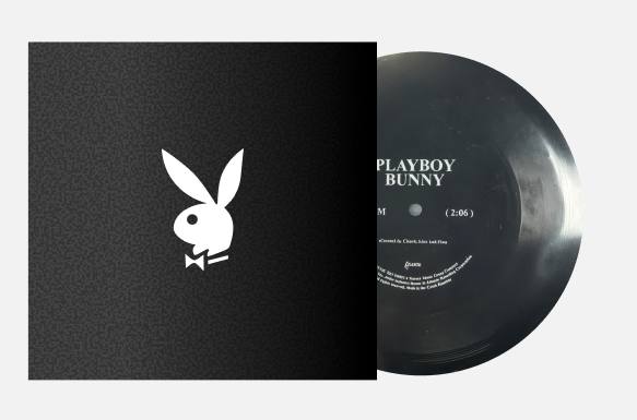 A vinyl record partially pulled from its sleeve, showing the Playboy bunny logo on the black cover and the black record with white text on a light gray background.