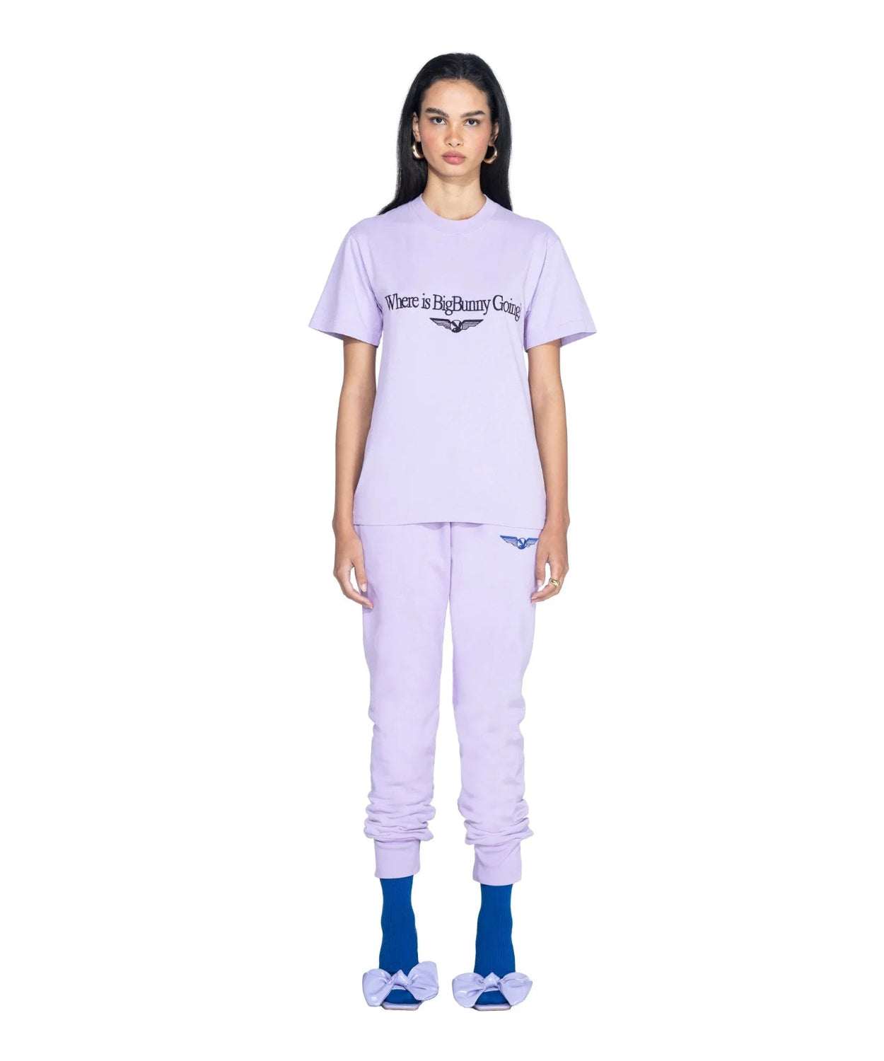 Woman wearing lavender 'Where is Big Bunny Going' graphic t-shirt, matching joggers, blue socks and bow sandals