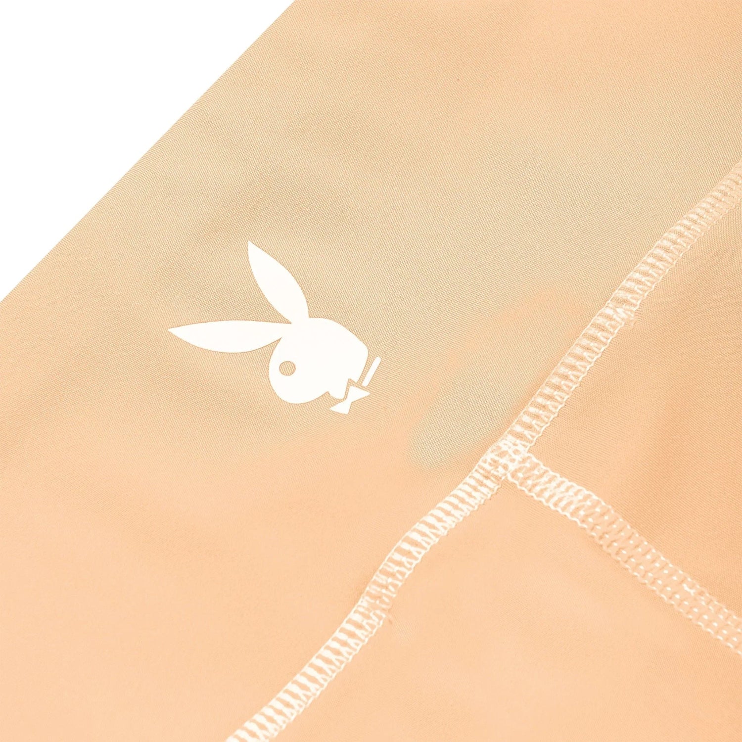 Close-up of beige women's active bike shorts with white bunny logo and visible stitching