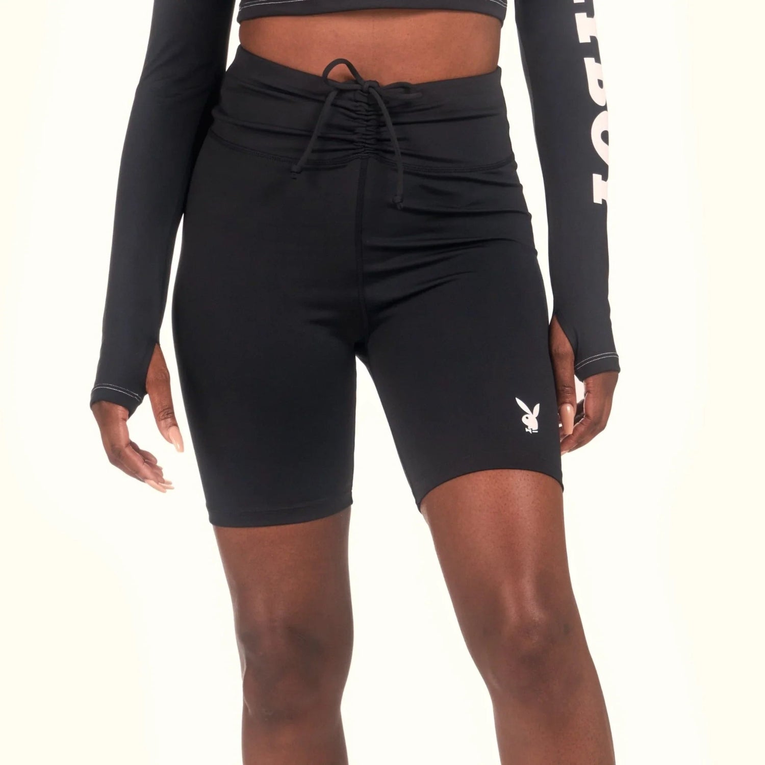 Black women's ruched tie bike shorts with white bunny logo, modeled on light background