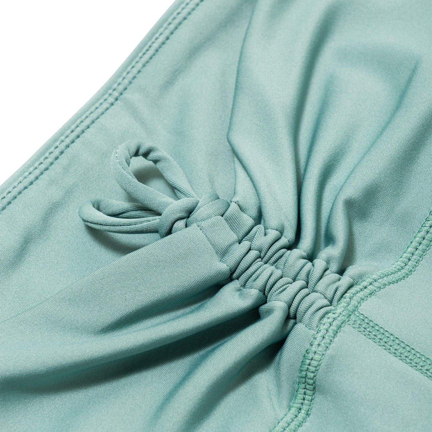 Close-up of teal ruched tie detail on women's active bike shorts
