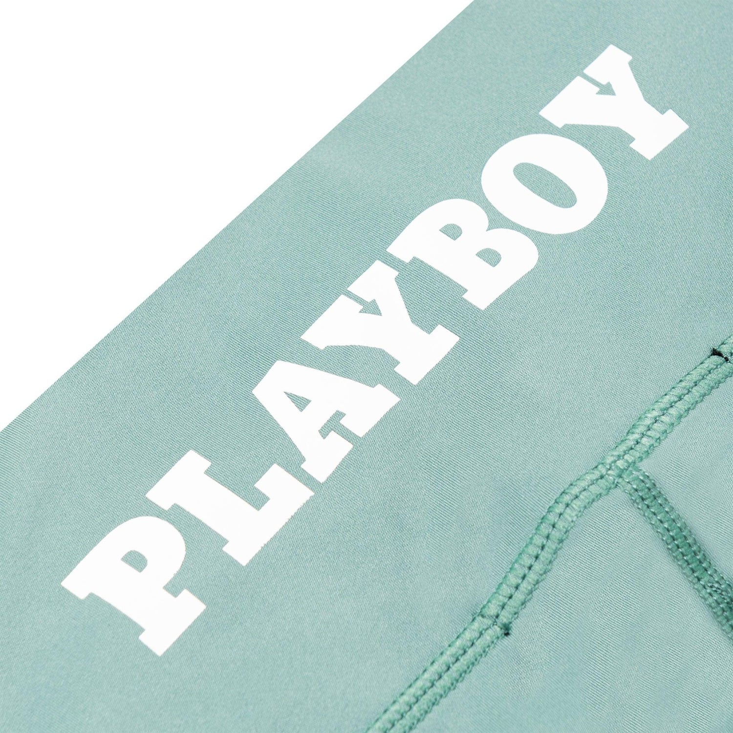 Sage green ruched bike shorts with white PLAYBOY text and visible stitching detail