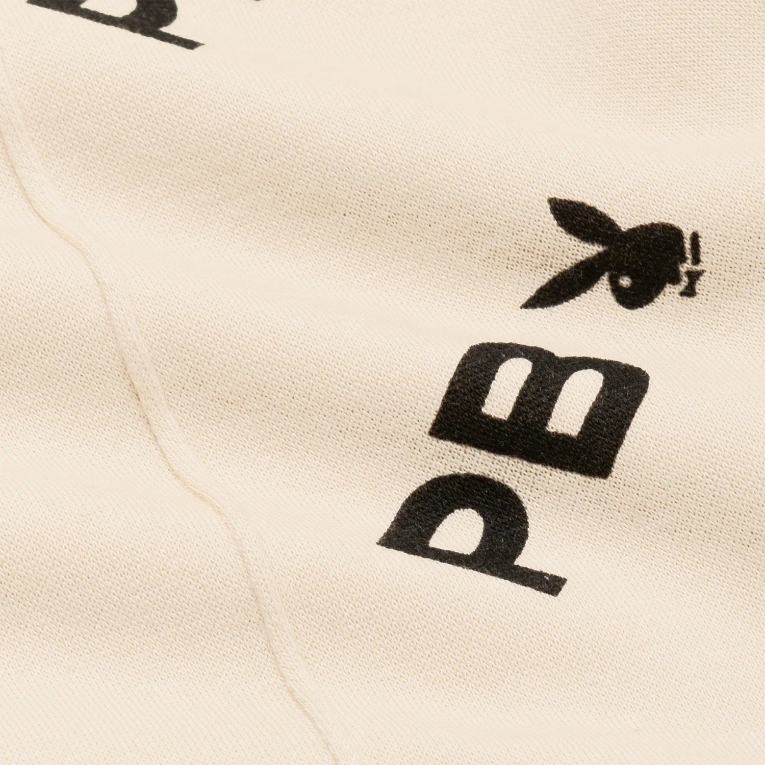 Close-up of beige joggers with black text and bunny logo detail