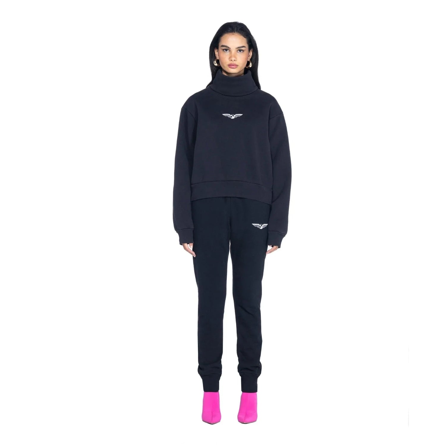 Woman wearing black aviation wings high neck cropped sweatshirt and joggers with pink shoes