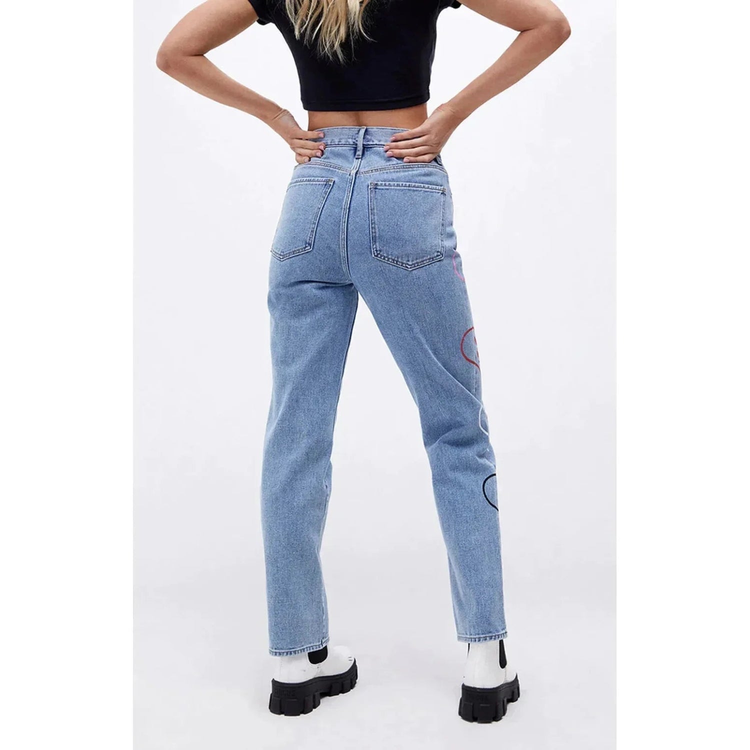 Back view of woman in light wash baggy denim pants with bunny and heart graphics
