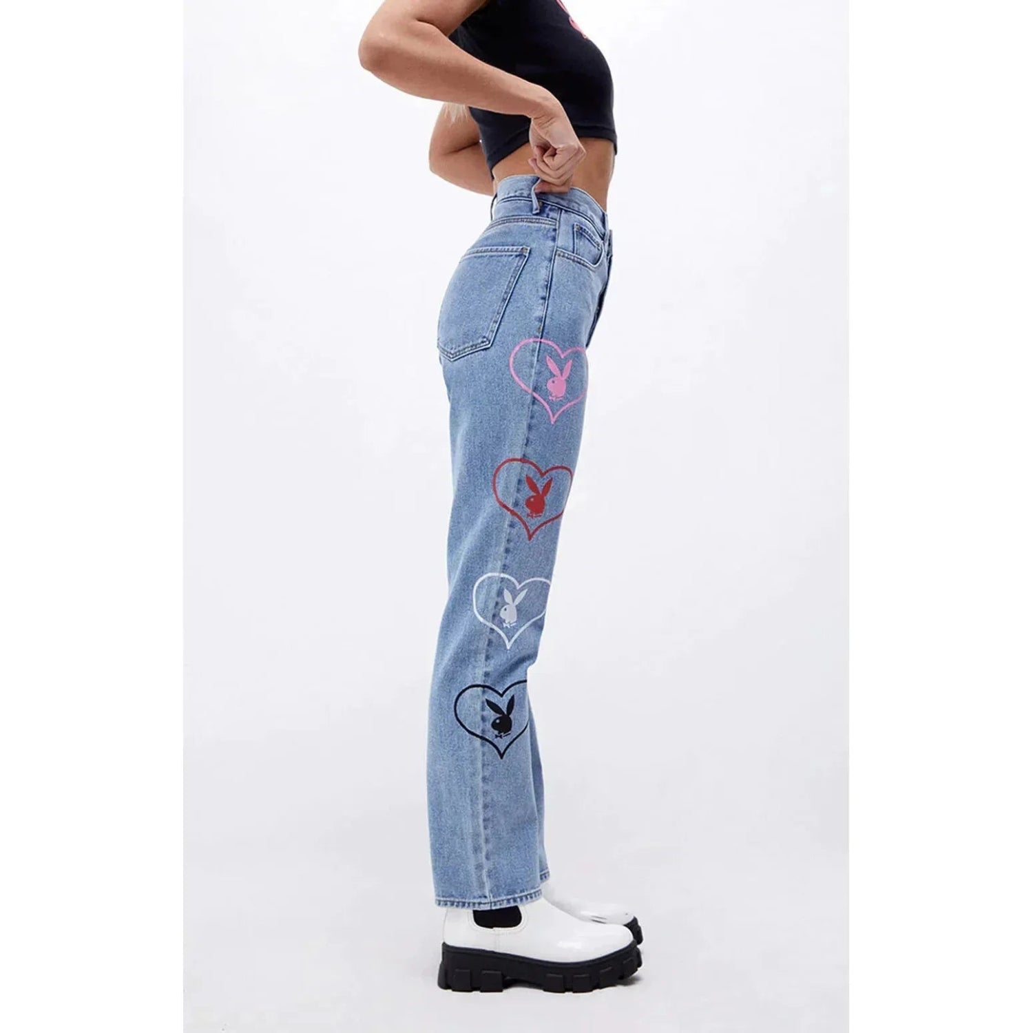 Woman wearing light blue baggy denim pants with colorful heart and bunny graphics along the side.
