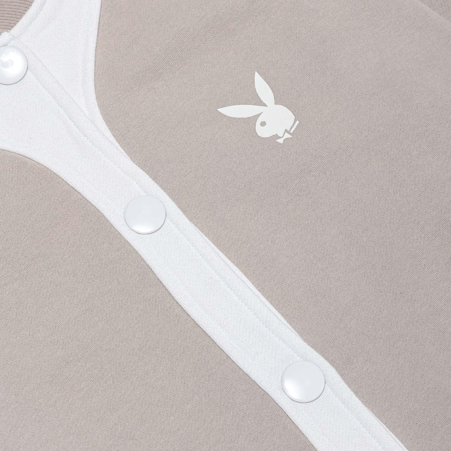 Close-up of beige women's bomber jacket with white buttons and bunny logo print