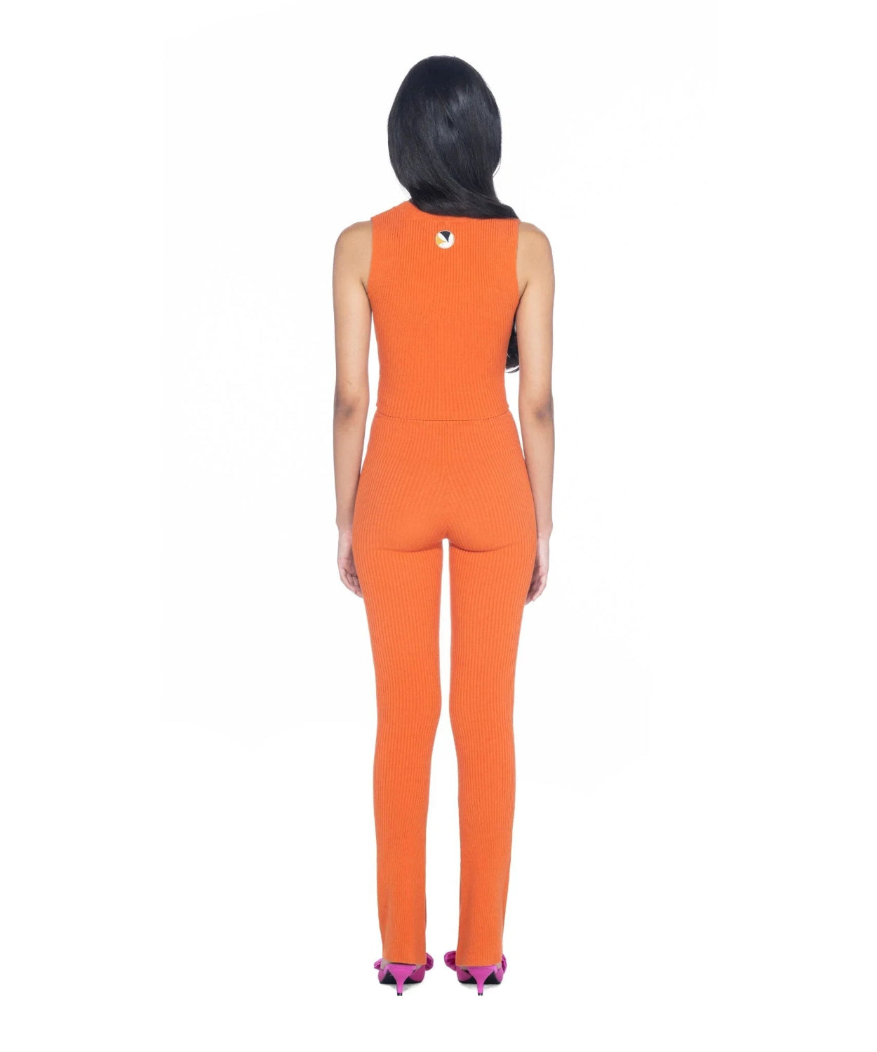 Woman wearing orange ribbed cropped tank top and matching pants, back view, studio setting