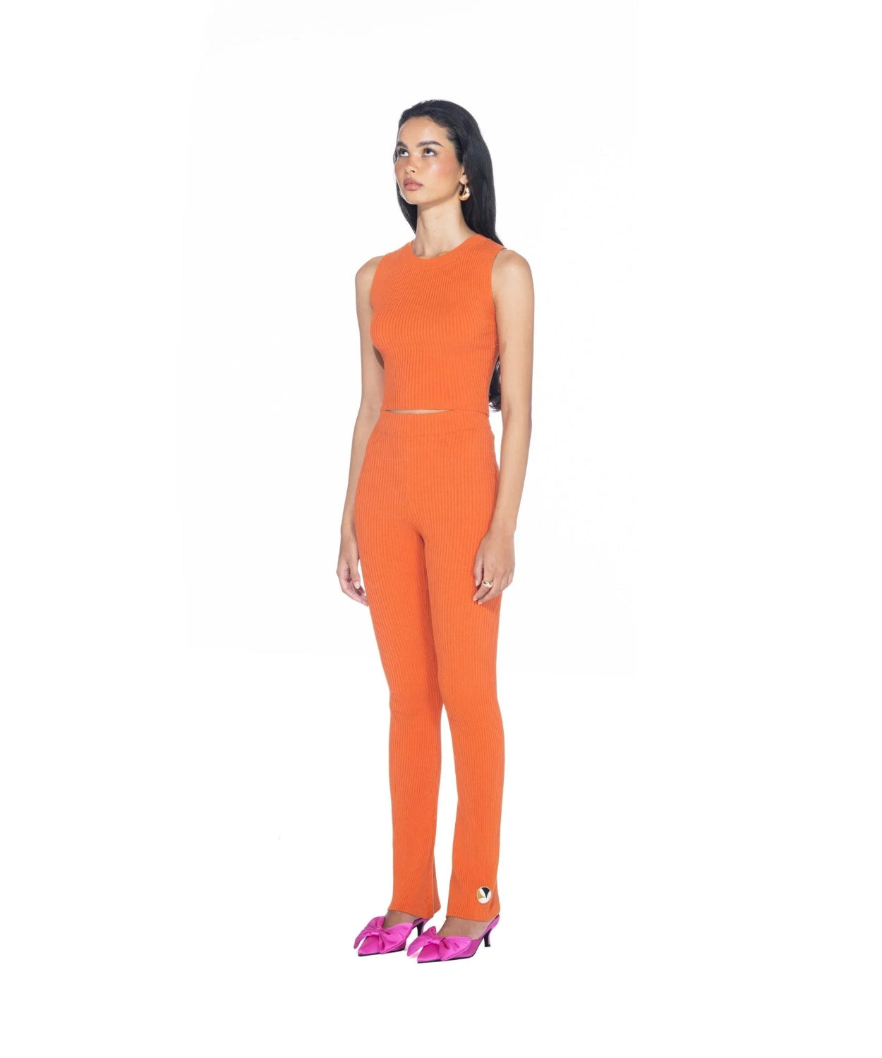 Woman wearing orange ribbed cropped tank top and matching pants with pink heels