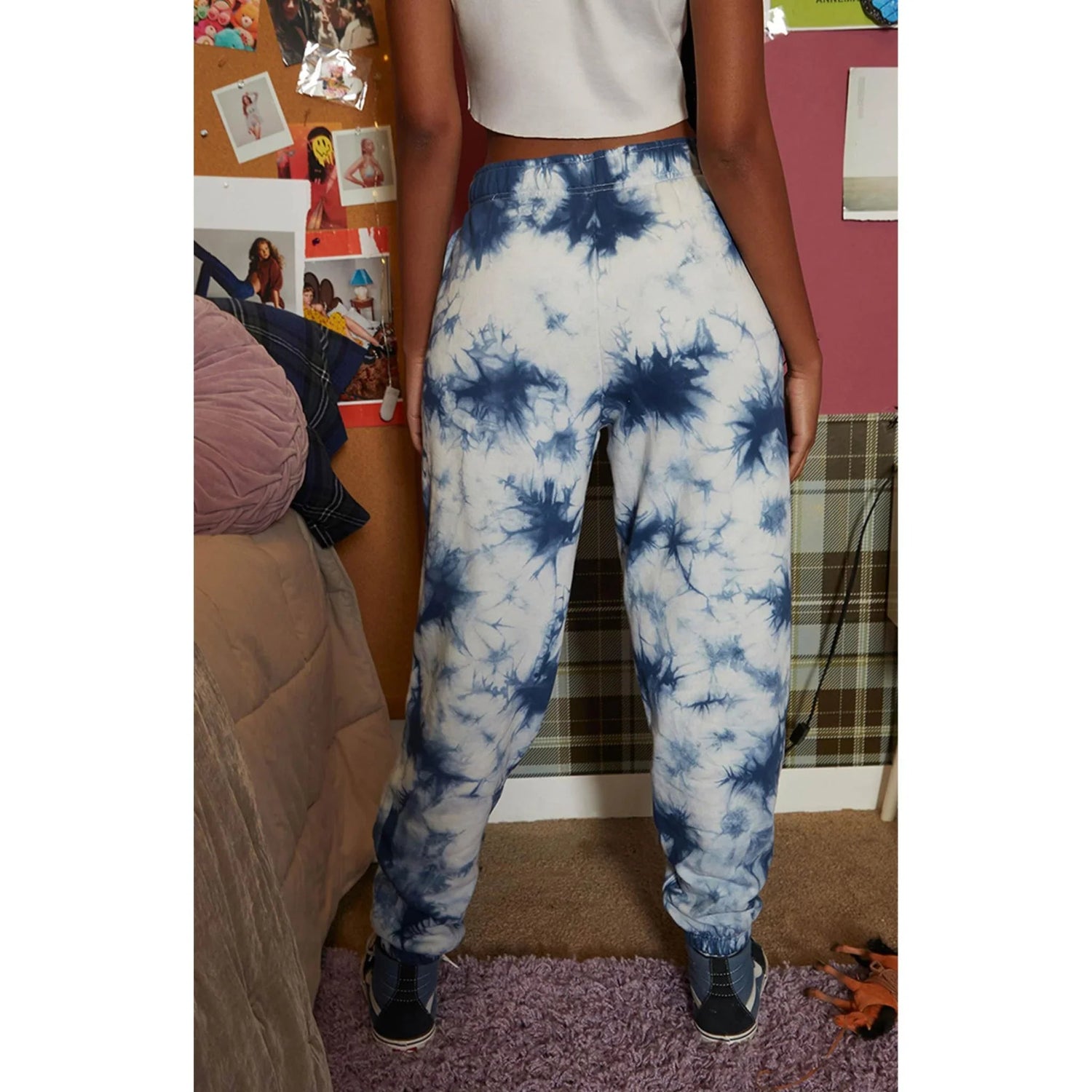 Woman wearing navy blue and white crystal tie-dye sweatpants in a casual bedroom setting