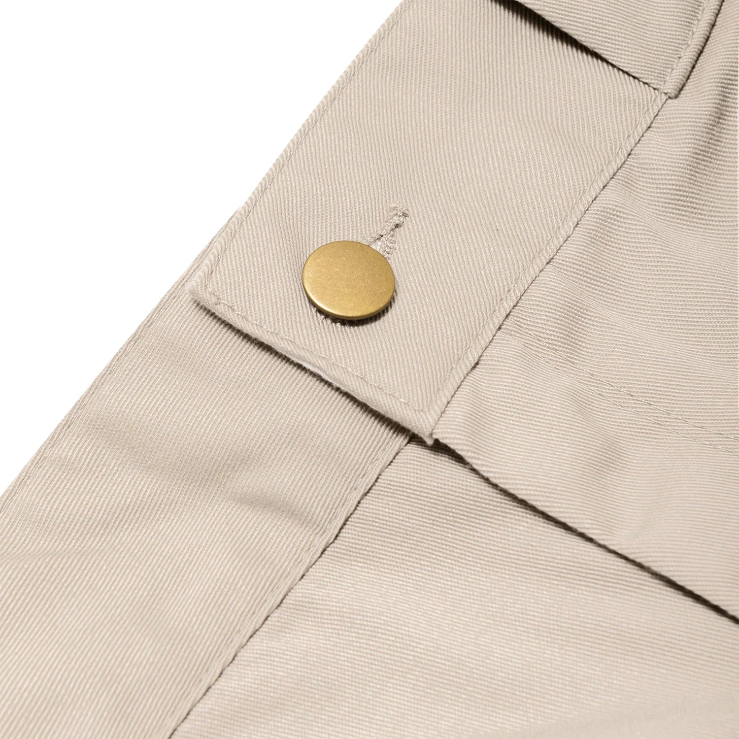 Close-up of beige women's work pants with gold button detail and textured fabric