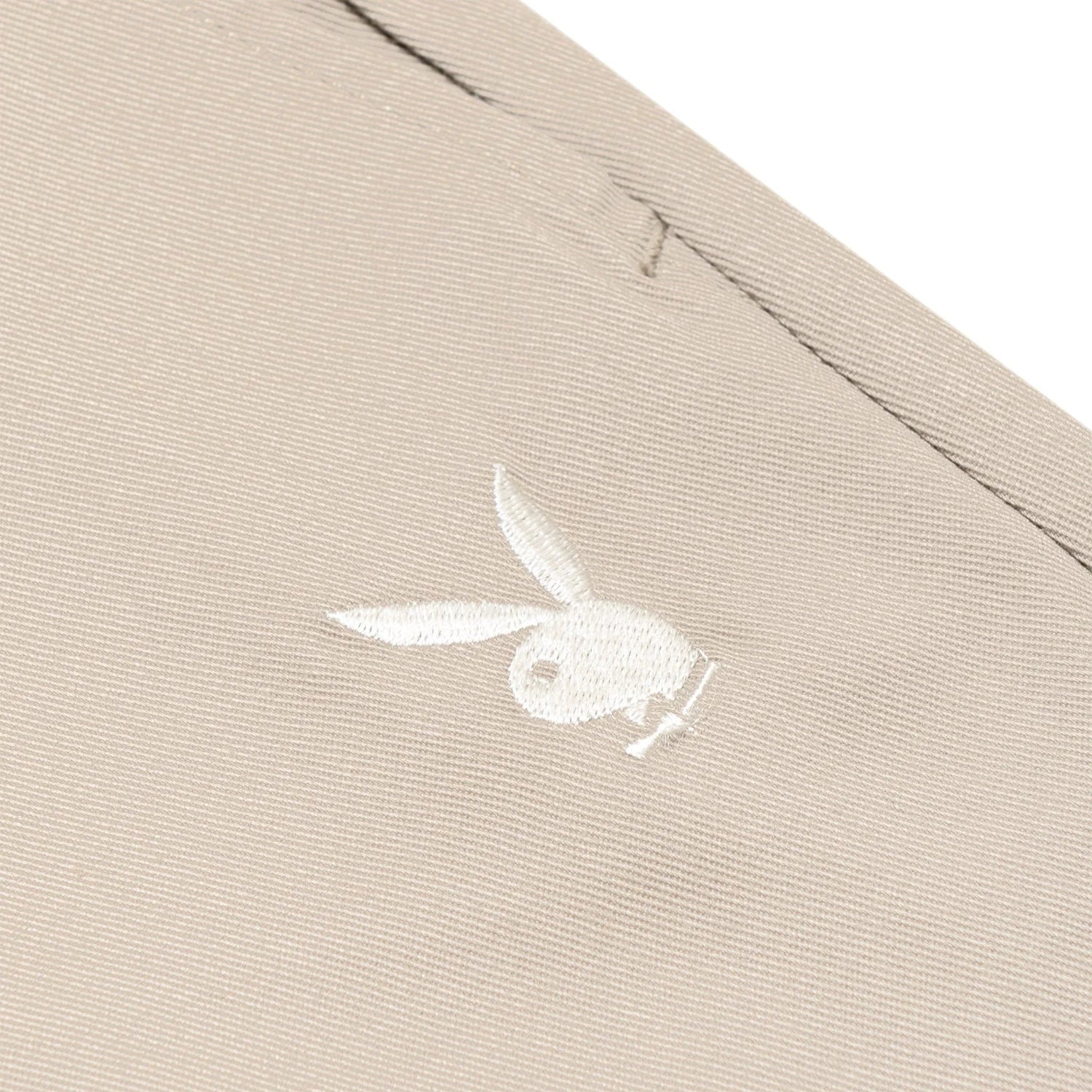 Beige women's pants close-up with embroidered white bunny logo on pocket