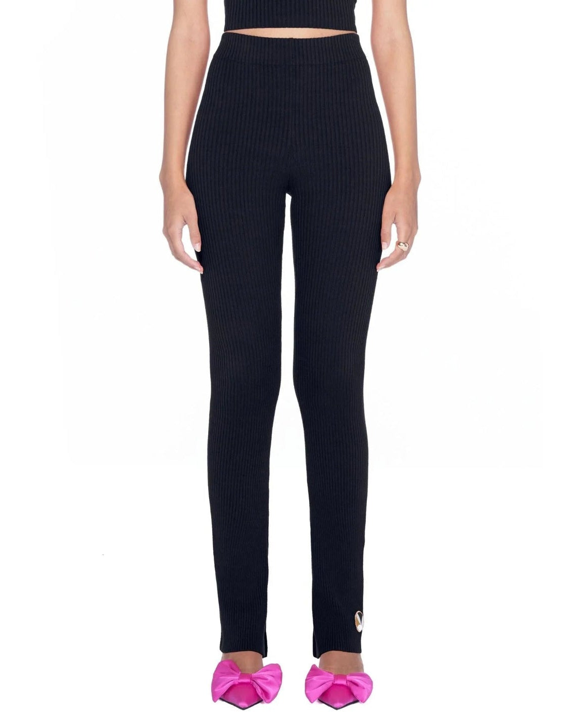Woman wearing black flared ribbed leggings with high waist, paired with pink bow heels