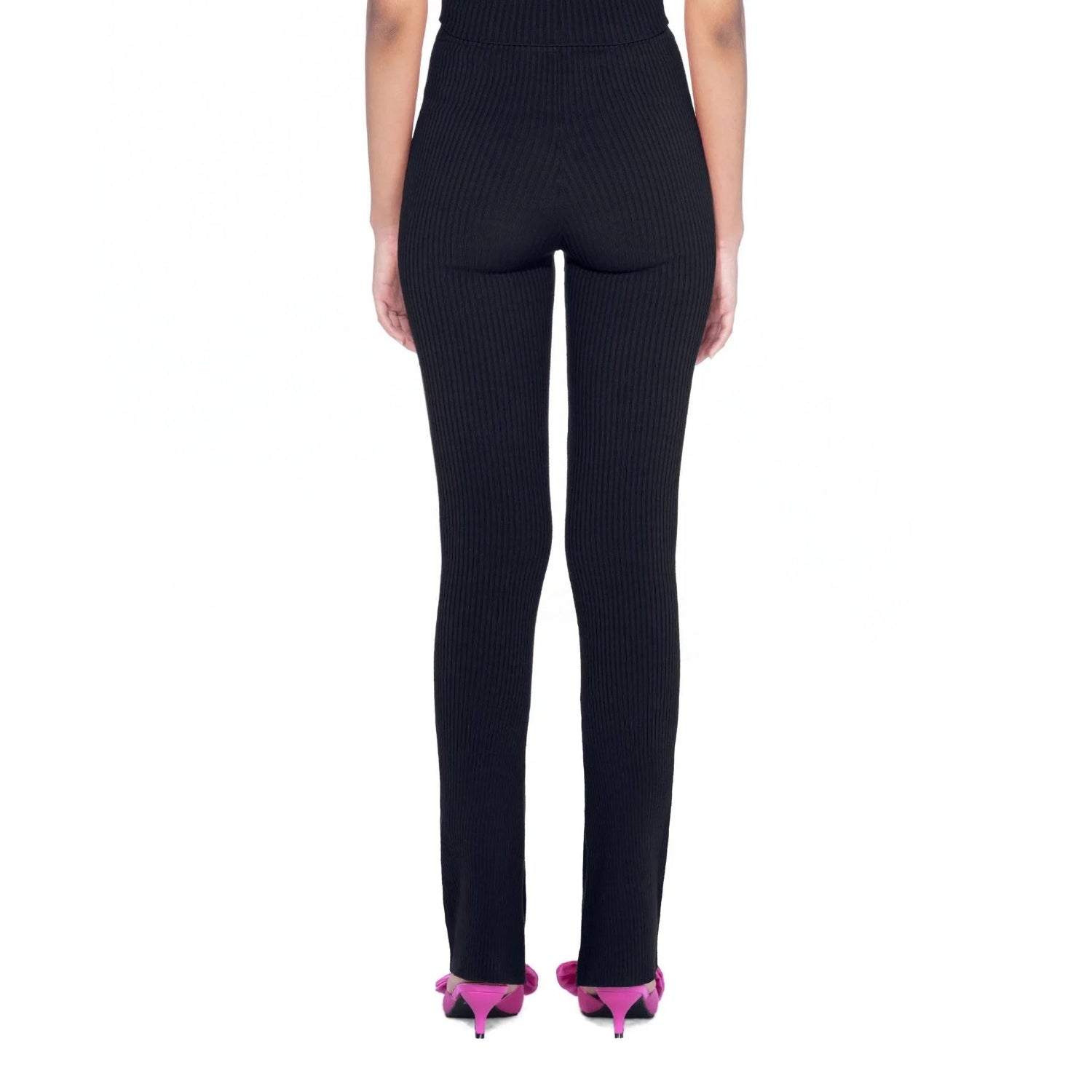 Back view of woman wearing black flared ribbed leggings and pink heels against white background