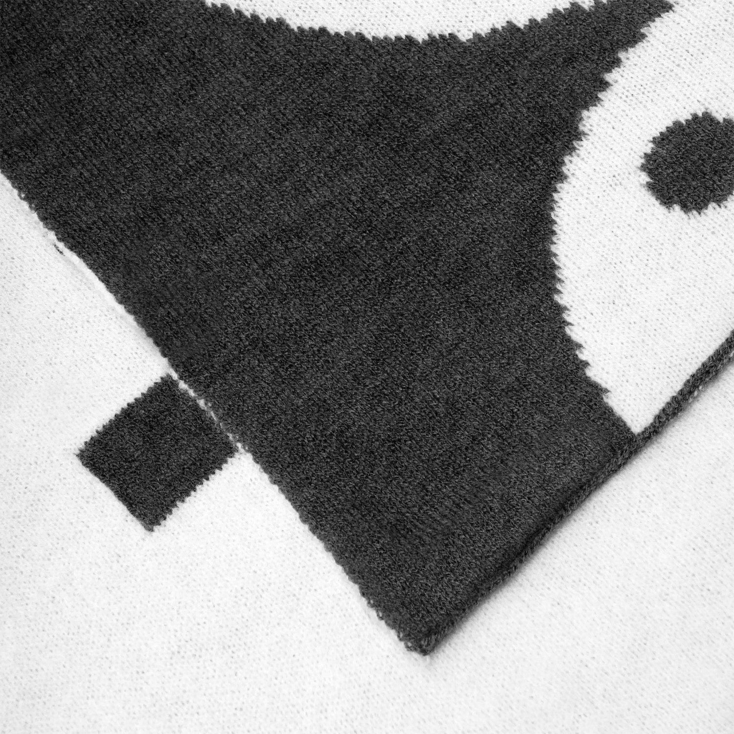 Close-up of black and white women's knit logo scarf with bold graphic pattern