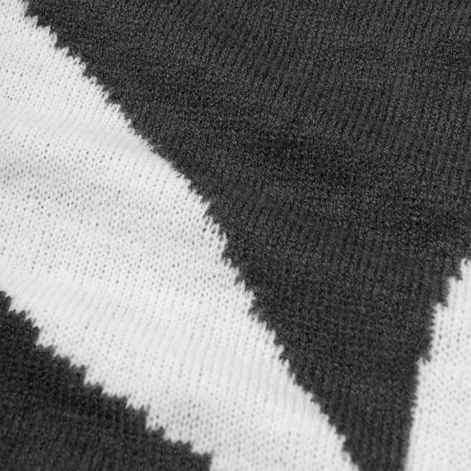 Close-up of black and white knit scarf with bold zigzag pattern, soft textured fabric