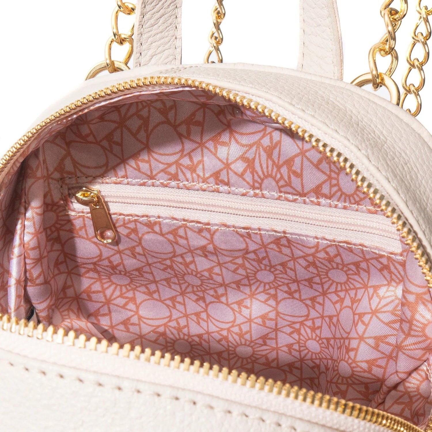 Close-up of cream leather mini backpack interior with pink geometric lining and gold zipper