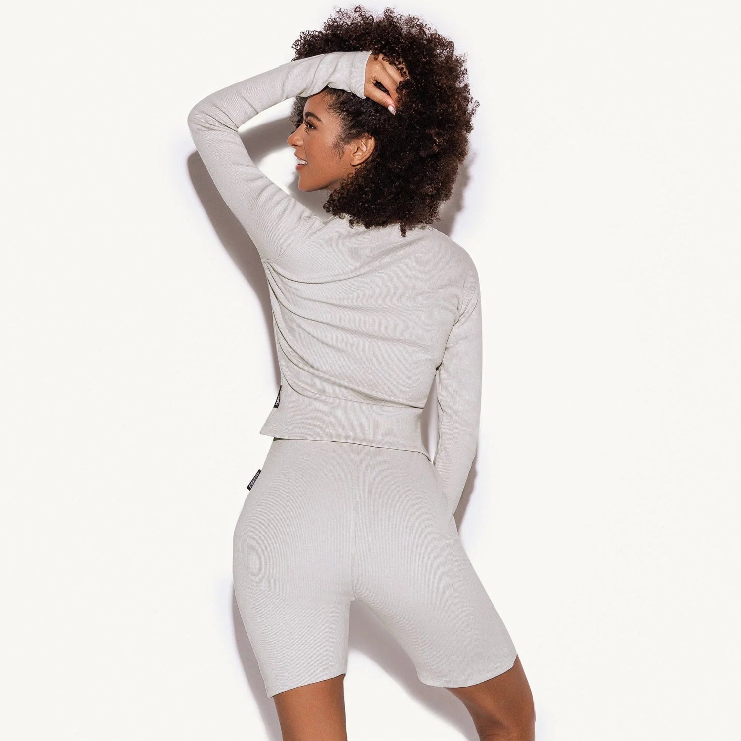 Woman modeling light grey ribbed lounge long sleeve top and shorts set, back view