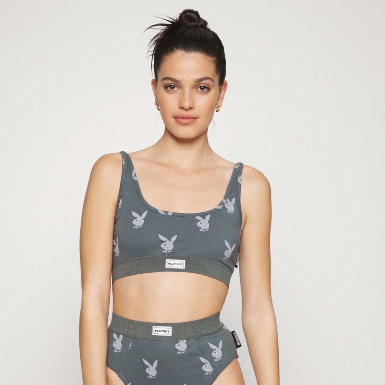 Woman wearing a gray lounge scoop neck bralette and matching high-waist underwear with bunny logo print