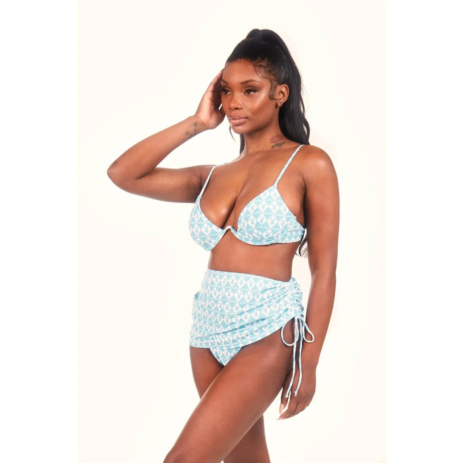 Woman wearing light blue monogram print bikini top and mini sarong with side tie