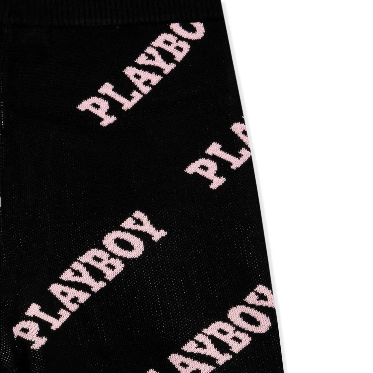 Black knit leggings with pink PLAYBOY text pattern, close-up of fabric detail