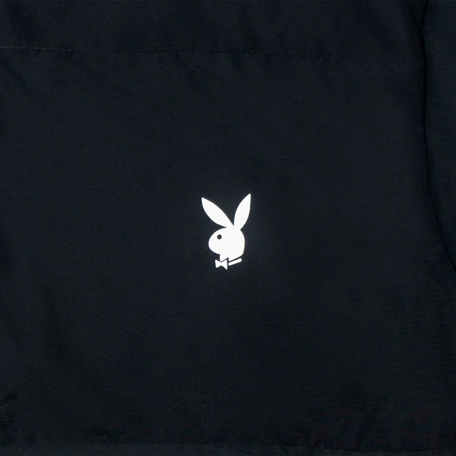 Close-up of black puffer vest with white rabbit head logo on fabric