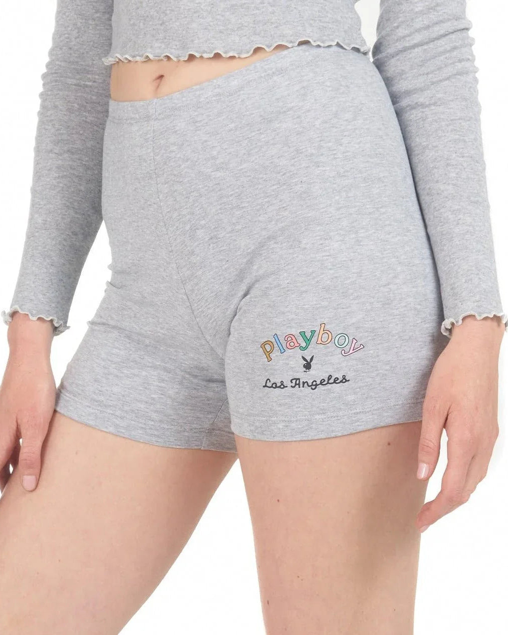 Woman wearing light grey bike shorts with rainbow Playboy Los Angeles logo