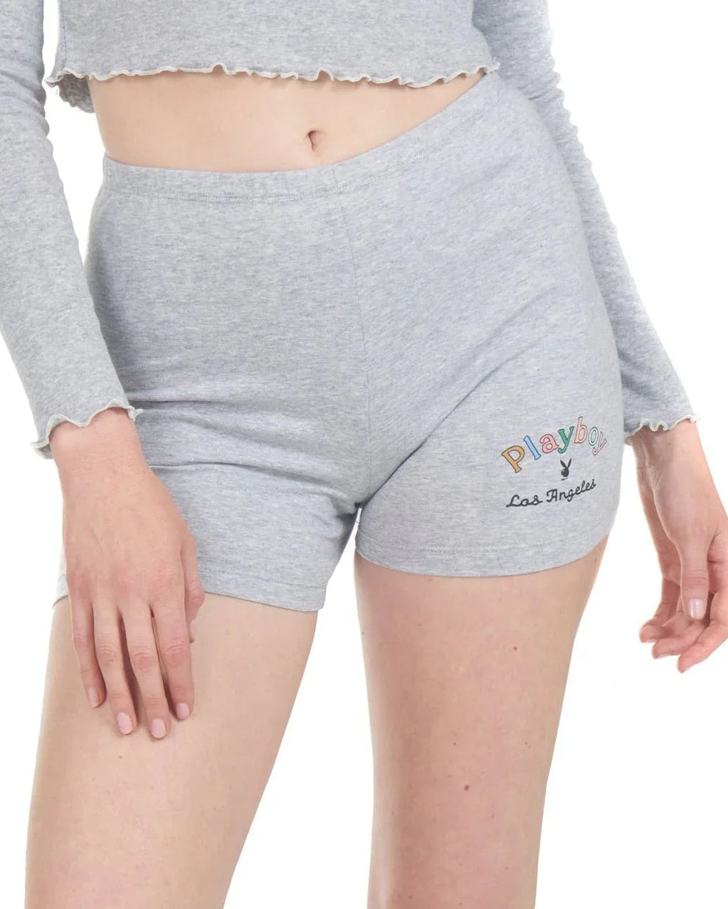 Woman wearing light grey bike shorts with rainbow text and Los Angeles embroidery