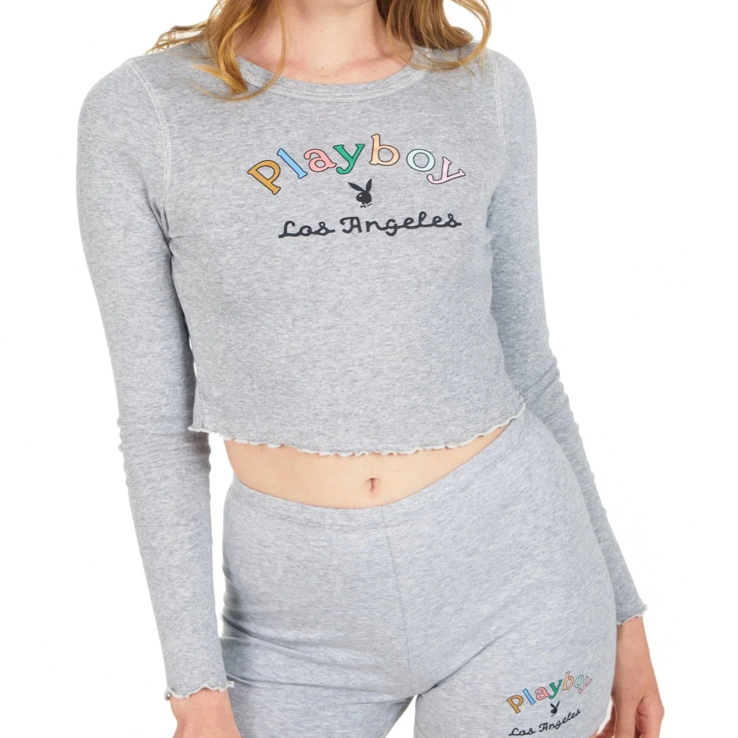 Woman wearing grey long sleeve crop top with rainbow logo and 'Los Angeles' text
