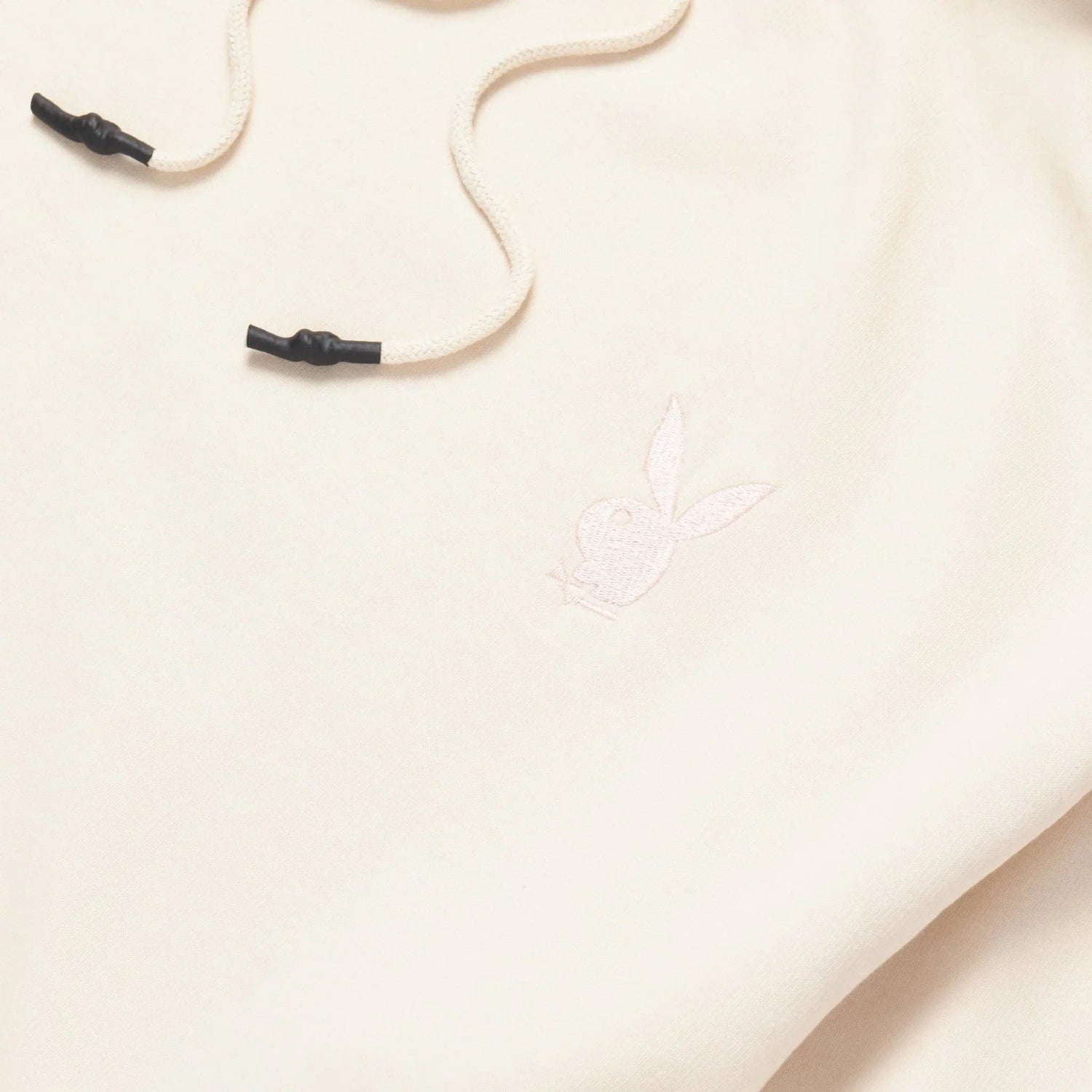 Cream hoodie dress detail with subtle bunny logo embroidery and drawstring cords