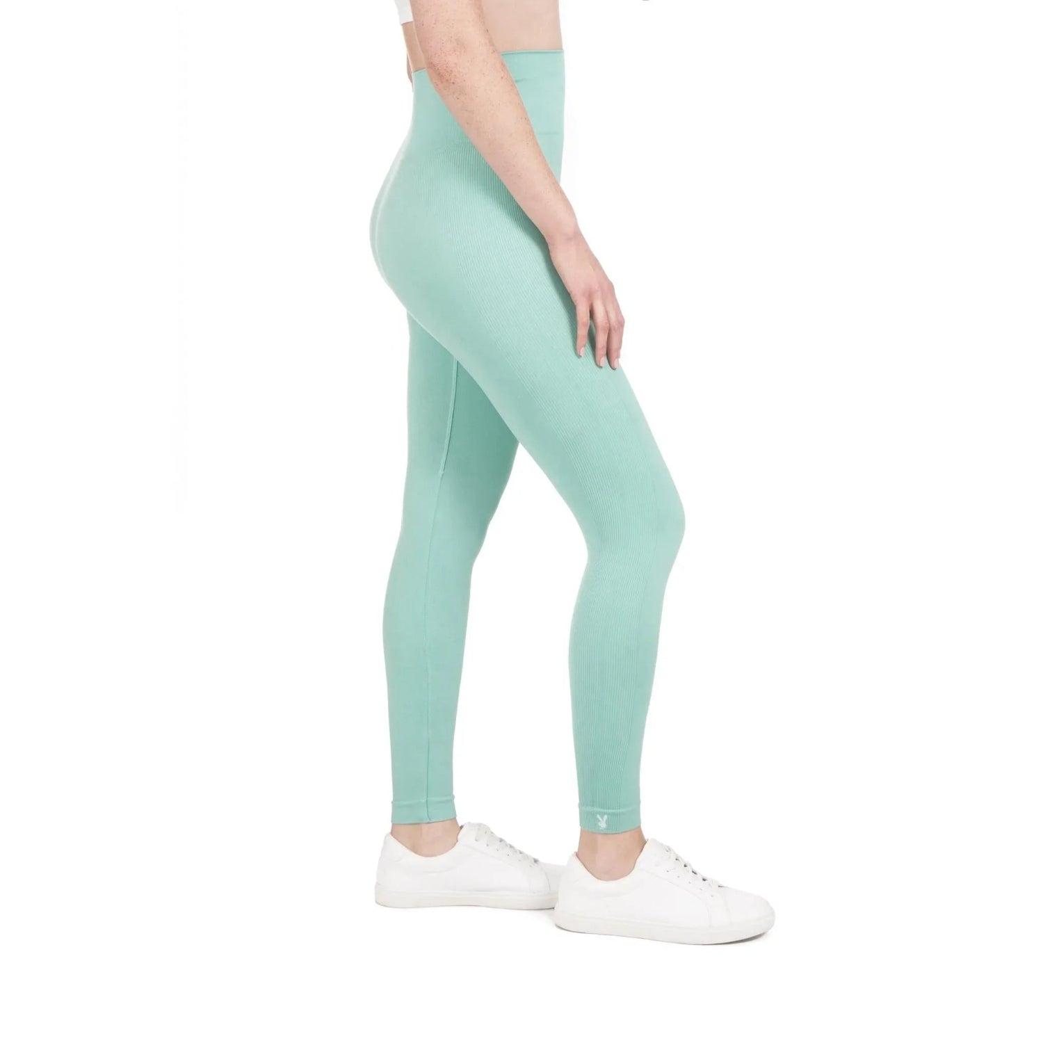 Woman wearing mint green ribbed sport leggings and white sneakers, side view