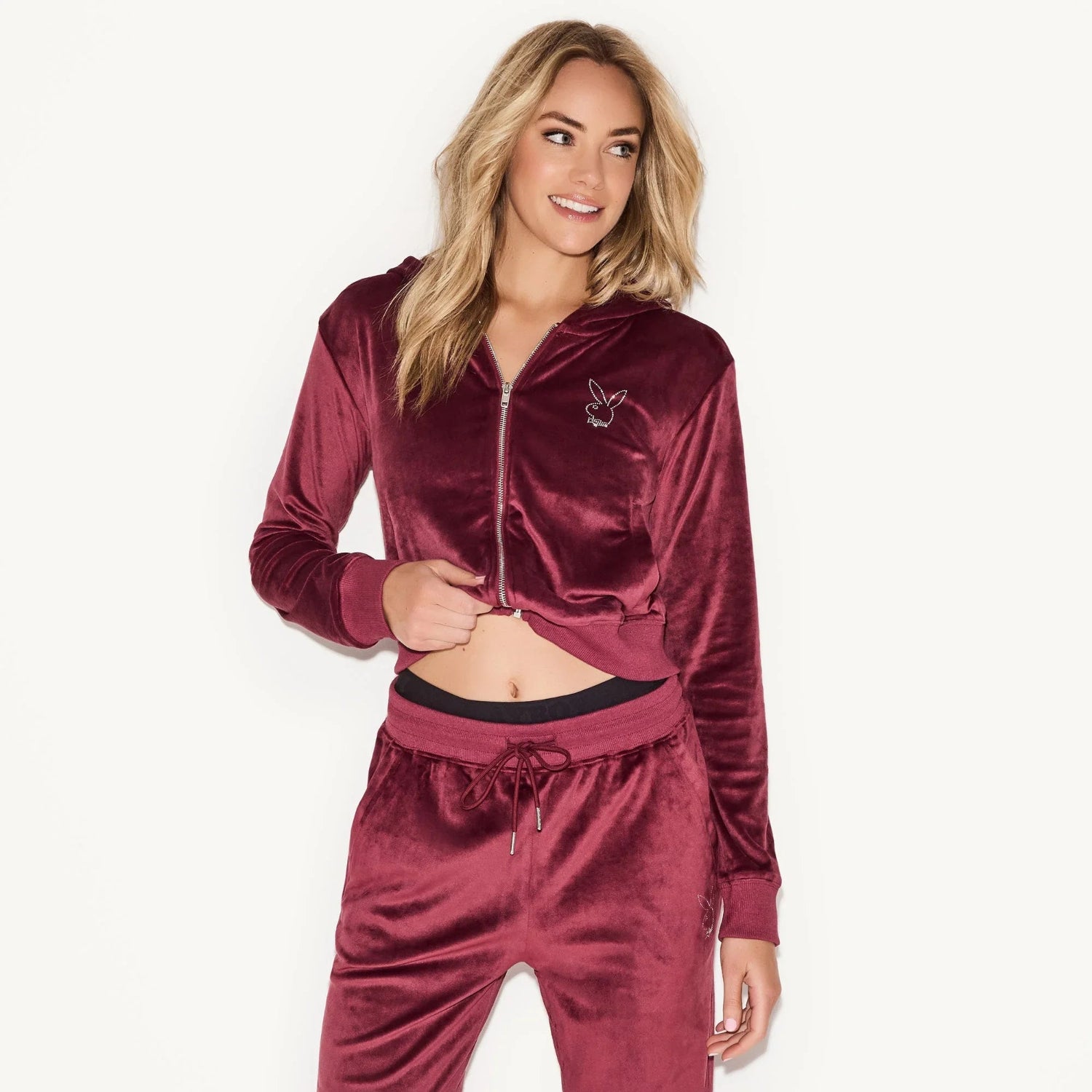 Woman wearing maroon velour zip-up jacket with hood and bunny logo, matching joggers