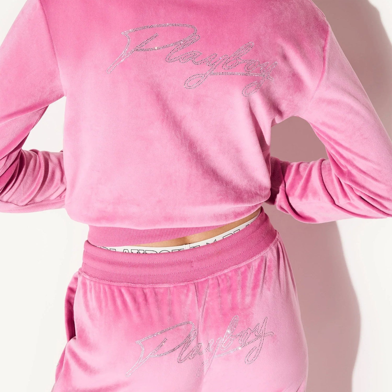 Pink velour women's jacket and pants set with rhinestone script on back and waistband detail