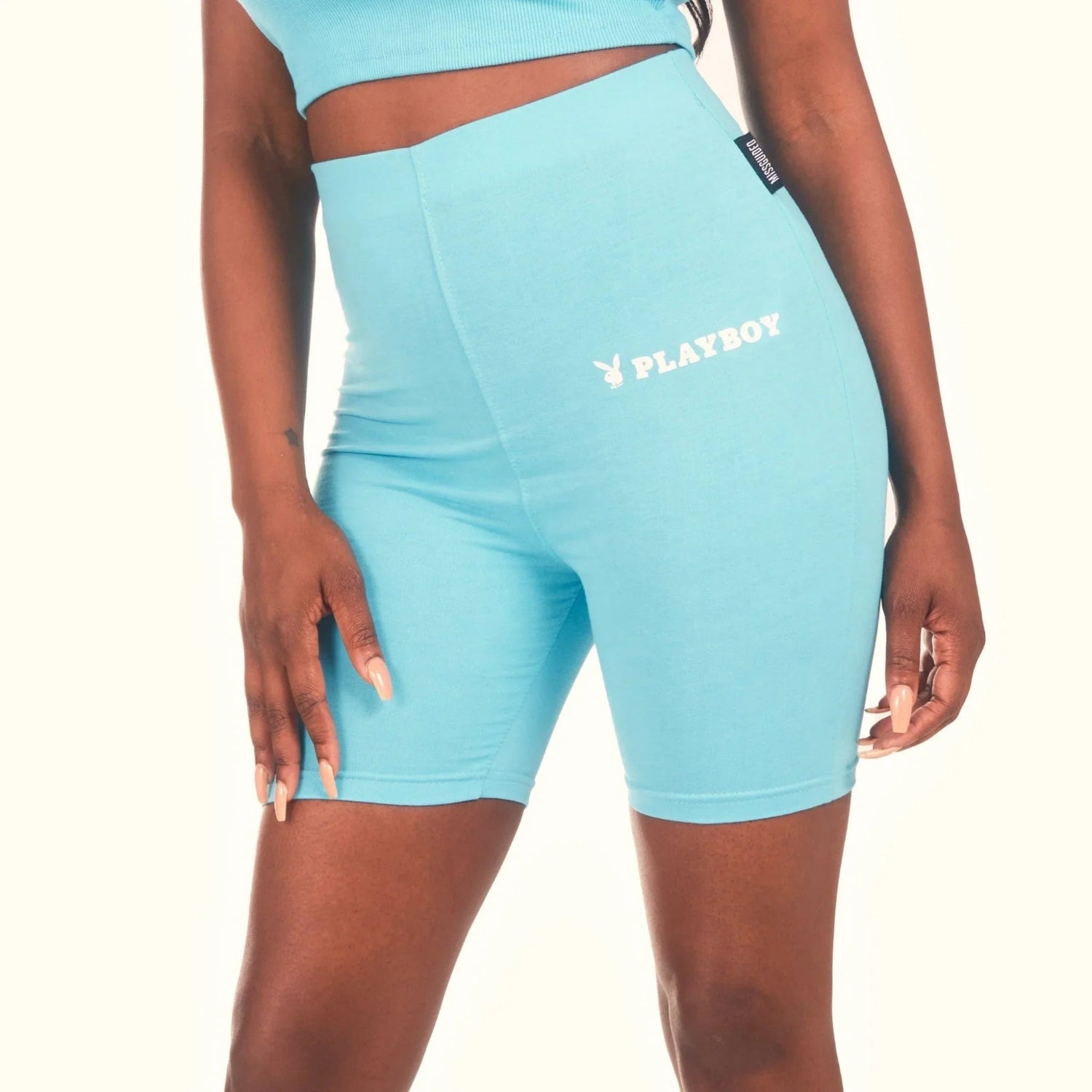Woman wearing light blue high-waisted biker shorts with white Playboy logo print