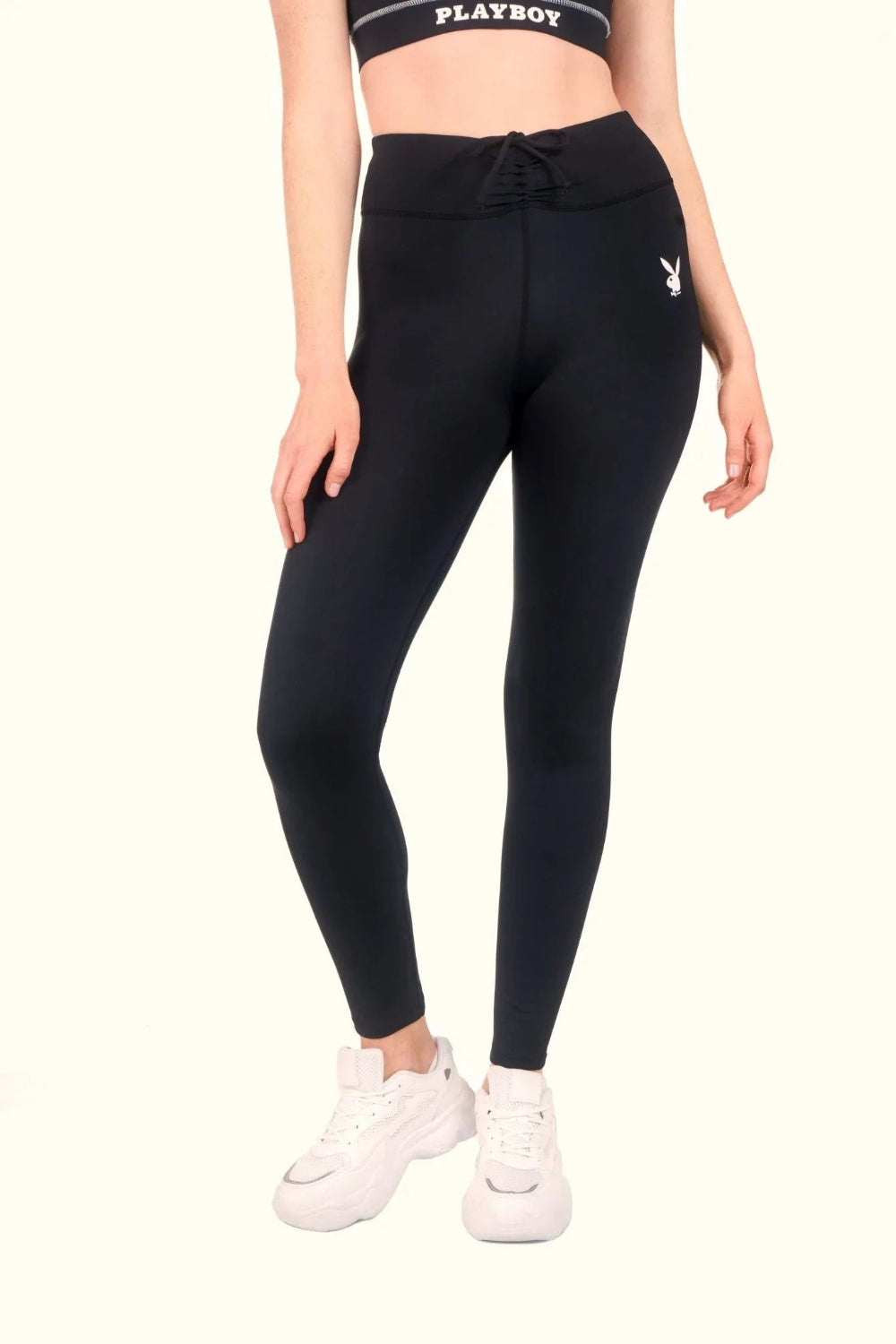 Woman wearing black ruched waistband leggings with high rise and sneaker shoes