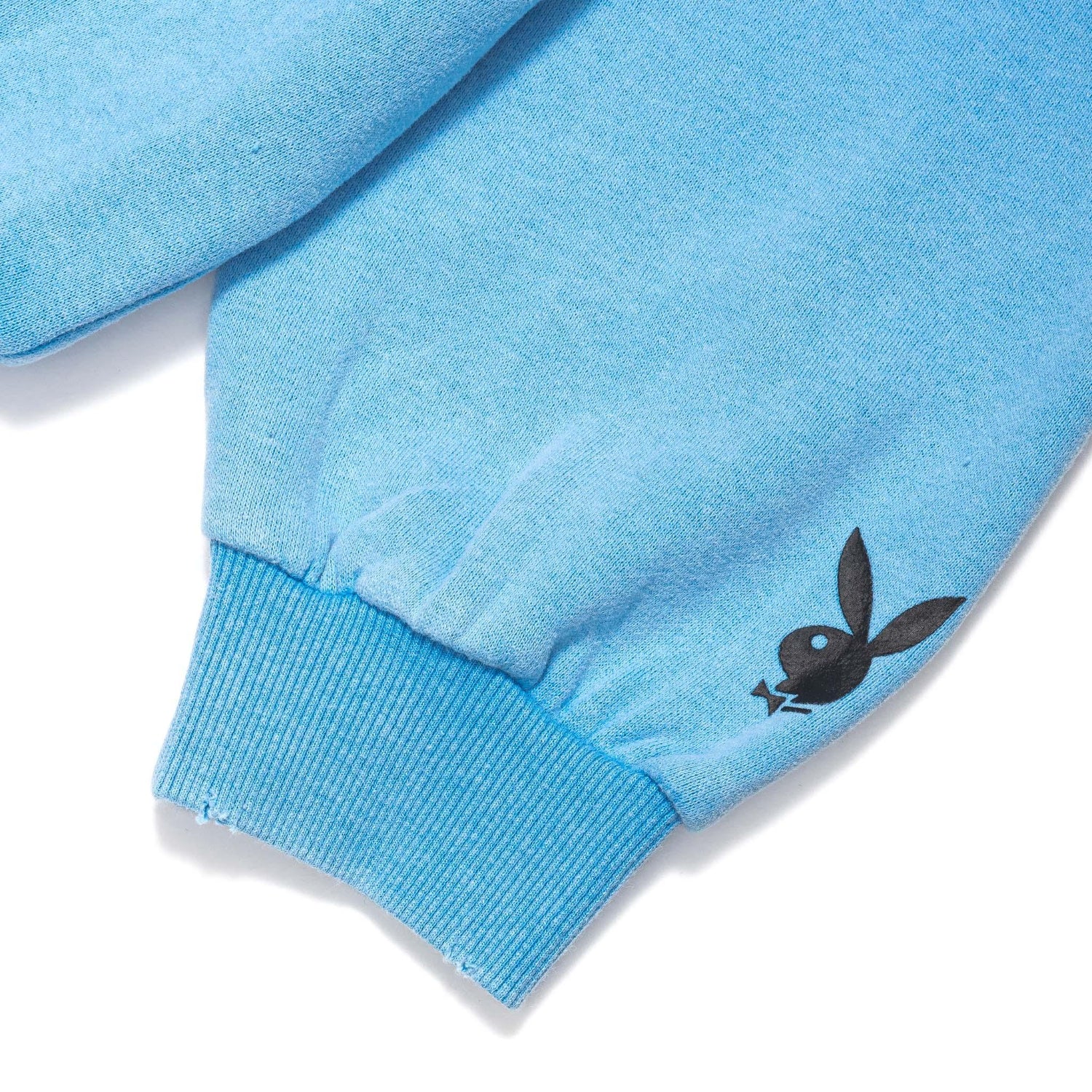 Light blue hoodie sleeve with black bunny logo and ribbed cuff, closeup view