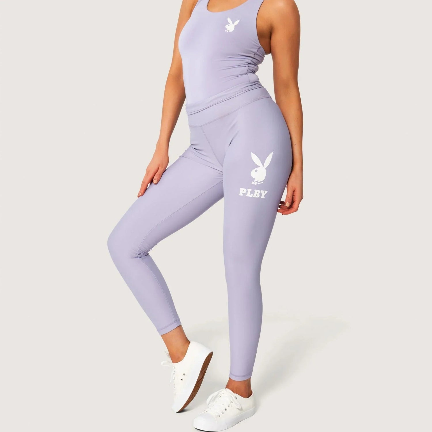 Woman wearing lilac leggings with white rabbit head logo and matching tank top
